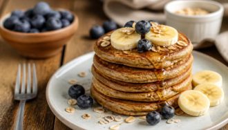 Pancakes aux flocons d'avoine healthy dorés dans une poêle antiadhésive, garnis de fruits frais et d'un filet de sirop d'érable, vus de dessus sur une table en bois clair