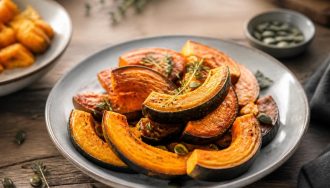 Velouté de courge musquée servi dans un bol en céramique blanche, garni de crème fraîche et de graines de courge grillées, sur une table en bois d'automne